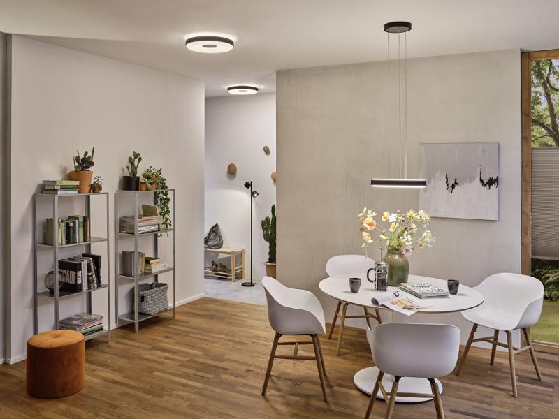 Moderner Essbereich mit weißem Tisch, Stühlen und schwarzer LED-Pendelleuchte aus Metall, Holzfußboden