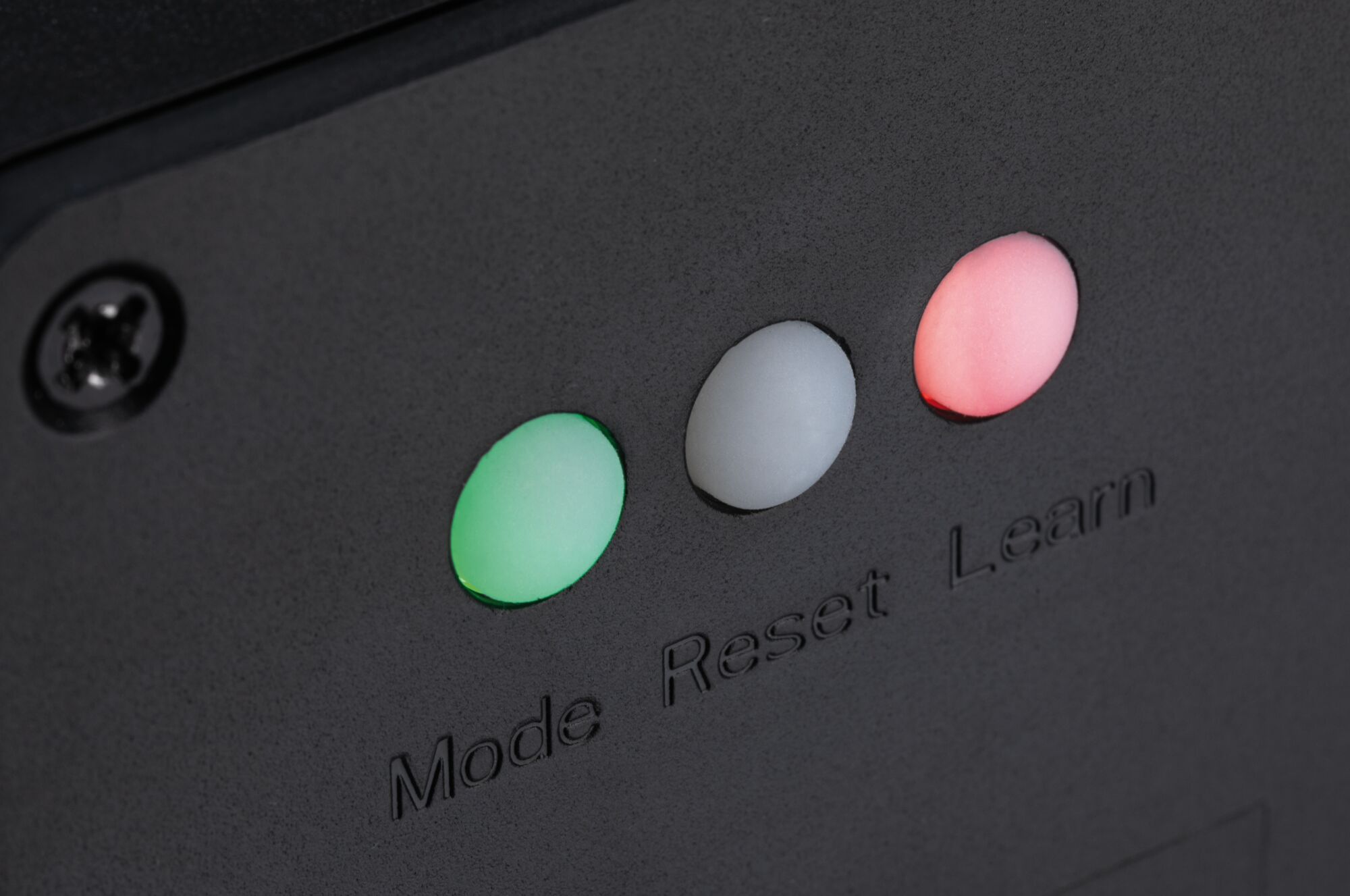 Close-up van drie LED-indicatoren in groen, wit en rood op zwart plastic met tekst Mode Reset Learn.