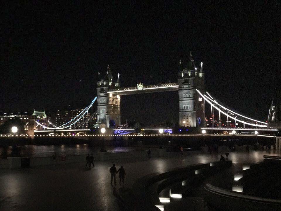 Beleuchtete Tower Bridge in London bei Nacht mit LED-Lichtakzenten und Flussufer im Vordergrund.