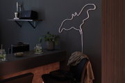 White LED neon flamingo light on dark wall in modern living space with bar and plant decor