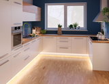 Moderne weiße Küche mit Holzarbeitsplatten und LED-Bodenbeleuchtung für stilvolles Küchendesign.
