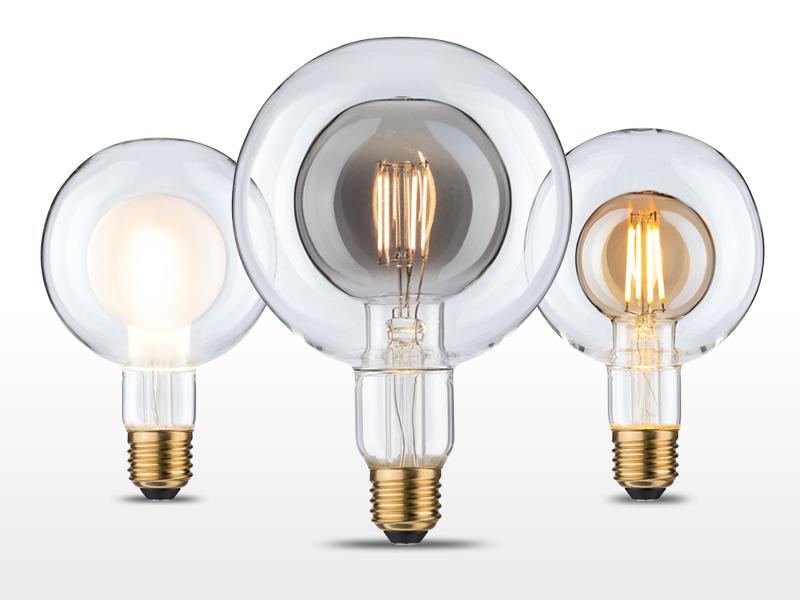 Drei dekorative Glühbirnen mit klaren Glaskugeln und sichtbaren Filamenten, E27 Fassung, LED Leuchtmittel.