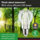 Clear LED light bulb with warm white glow in front of green forest background for energy-efficient lighting