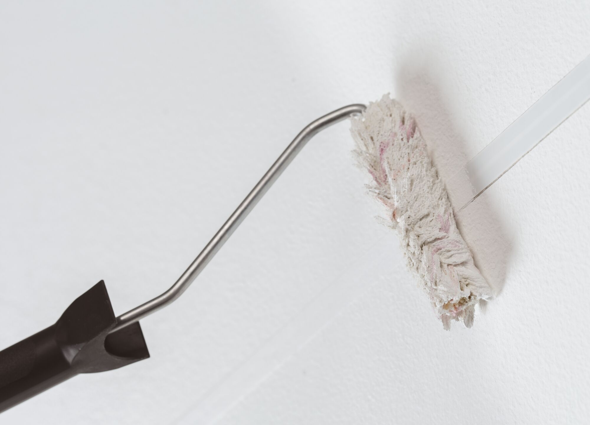 Farbroller mit schwarzem Griff und weißem, texturiertem Farbwalzenbezug für präzises Streichen von Wänden.