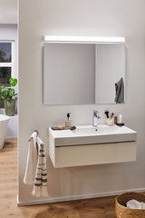 Modern bathroom with white wall-mounted sink, large mirror and LED mirror light for bathroom lighting