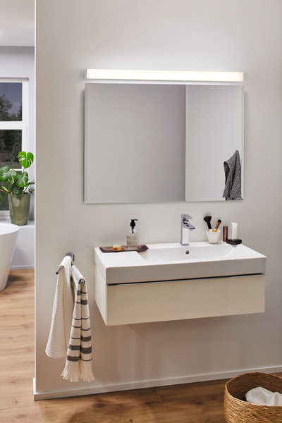 Modern bathroom with white wall-mounted sink, large mirror and LED mirror light for bathroom lighting