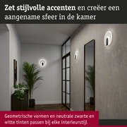 Moderne ronde witte wandlampen met zwarte accenten aan grijze muur in hal met spiegel en planten