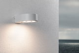 Runde weiße Außenwandleuchte aus Metall mit warmweißem LED-Licht an strukturierter Wand.