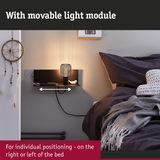 Black wall shelf with movable light module beside bed with dark bedding and dreamcatcher