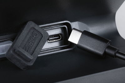 Close-up of black USB-C charging port with protective cap and cable on electronic device.