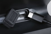 Close-up of black USB-C charging port with protective cap and cable on electronic device.