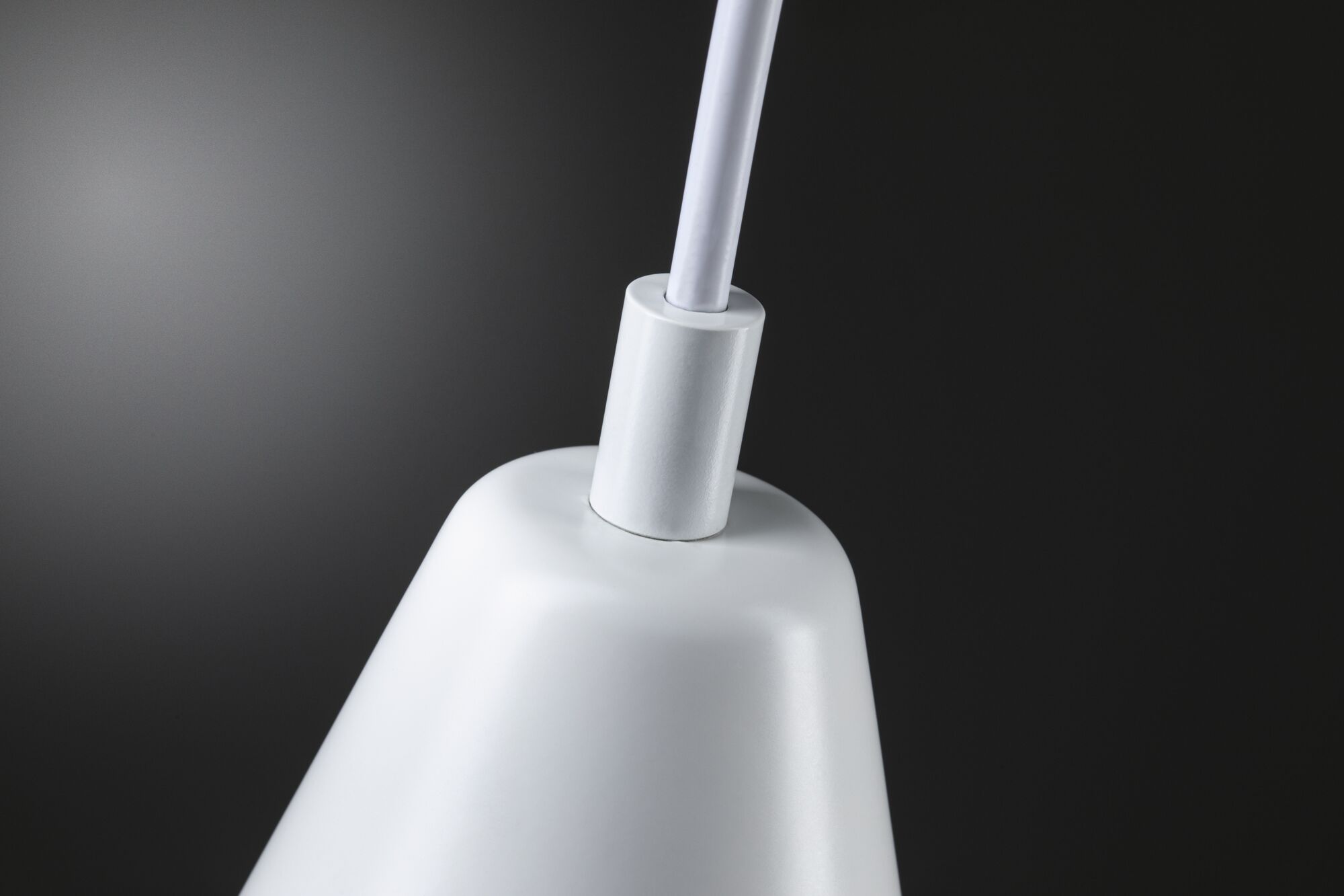 Gros plan d'un abat-jour blanc en métal avec connexion de câble sur fond sombre