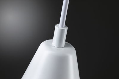 Gros plan d'un abat-jour blanc en métal avec connexion de câble sur fond sombre