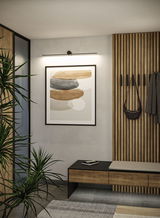 Black LED picture light above abstract art with wooden bench and coat rack in modern hallway