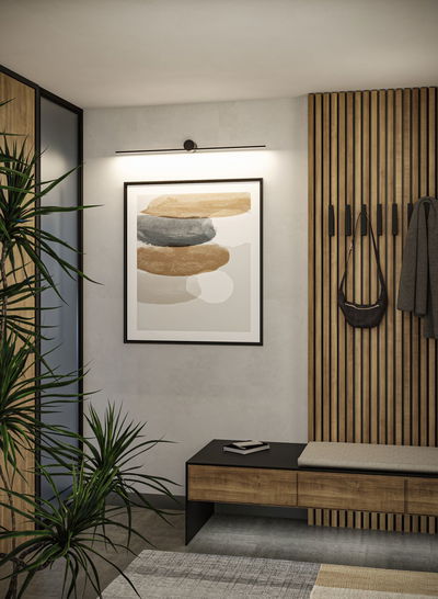 Black LED picture light above abstract art with wooden bench and coat rack in modern hallway
