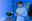 Mann in blauem Pullover steuert Smartphone in modernem Raum mit blauer LED-Beleuchtung und Pflanzen