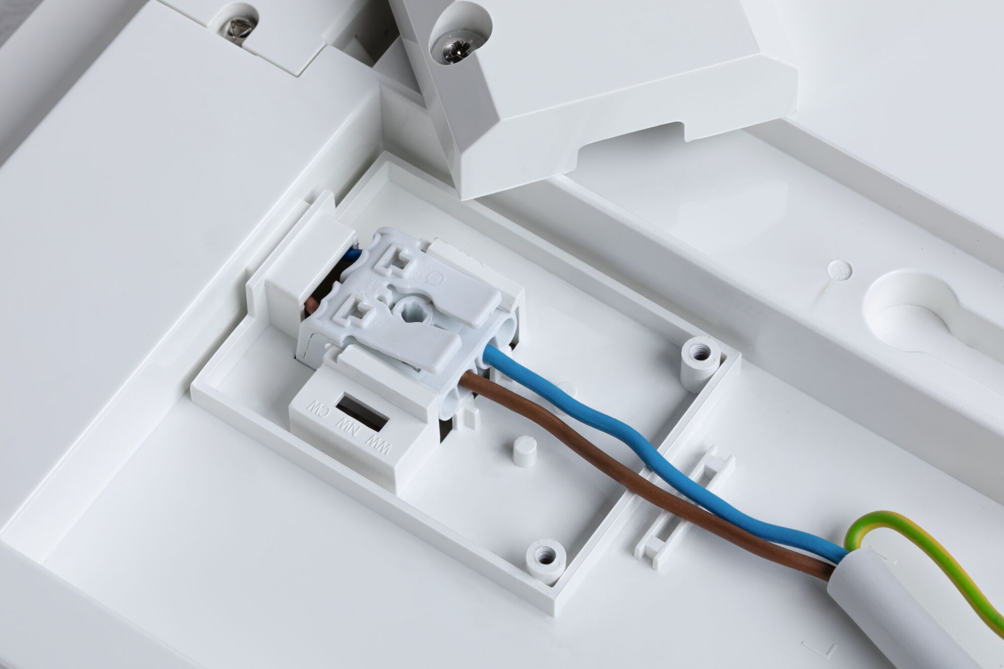Hvid plastikboks med elektrisk klemme og brune, blå ledninger til LED-belysning
