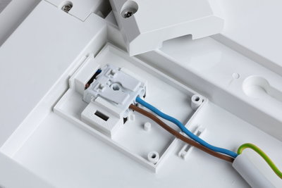 Hvid plastikboks med elektrisk klemme og brune, blå ledninger til LED-belysning