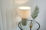 Lampe de table avec base en céramique grise et abat-jour en tissu blanc sur table d'appoint en verre