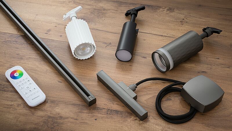 Différents spots LED URail gris et blanc avec télécommande sur table en bois pour éclairage moderne