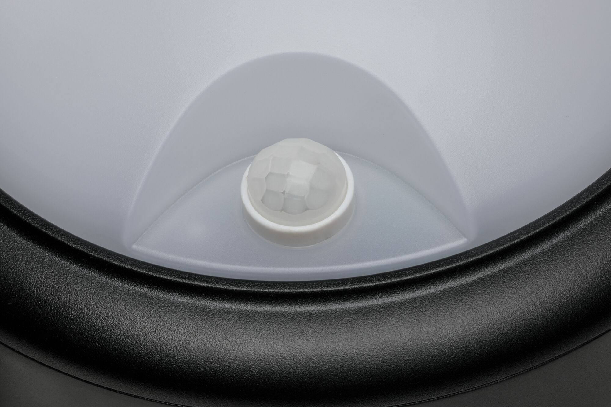 Gros plan d'un détecteur de mouvement blanc avec cadre en plastique noir pour éclairage LED