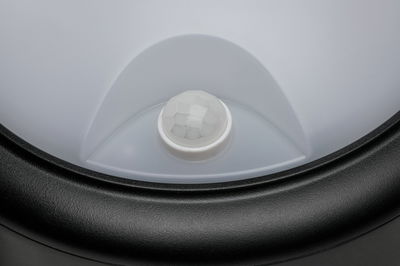 Gros plan d'un détecteur de mouvement blanc avec cadre en plastique noir pour éclairage LED