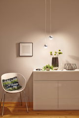 Modern white glossy cabinet with vase, plant, and hourglass, lit by two spherical pendant lights in warm room