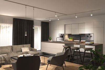Modernes Wohnzimmer mit offener Küche, weißen Schränken, Holzarbeitsplatte und LED-Deckenleuchten