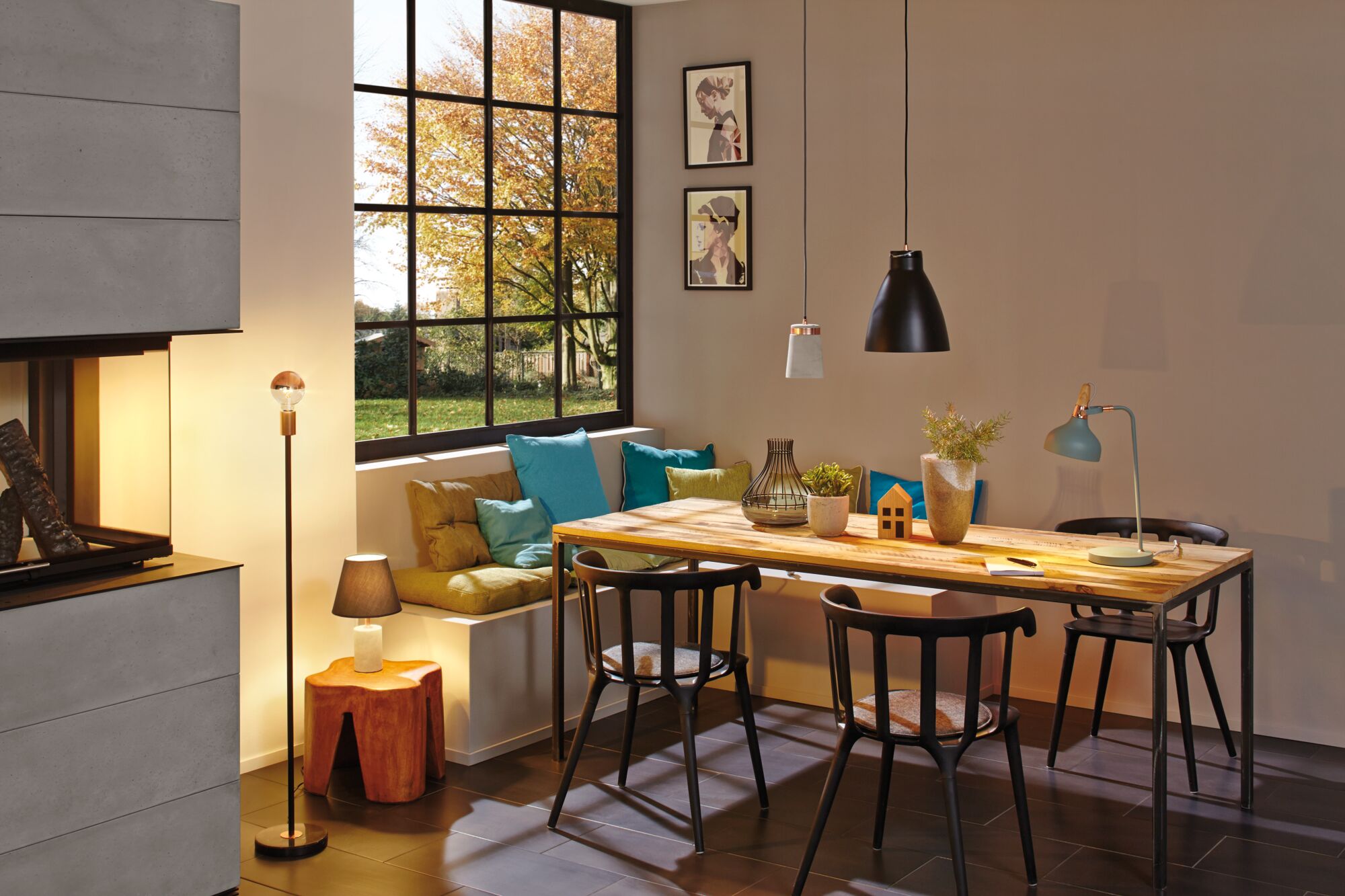 Moderne eetruimte met houten tafel, zwarte stoelen en diverse lampen met warm licht.