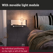 White wall shelf with movable light module and bulb beside bed with grey knitted cushion
