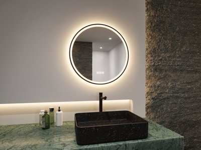 Round LED mirror with warm white light above black stone sink on green marble bathroom countertop.
