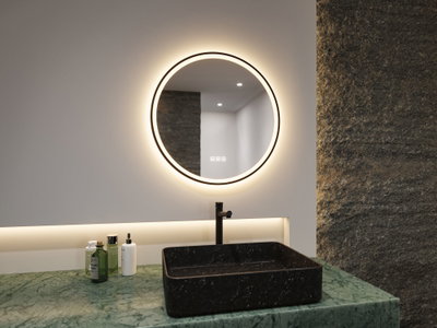 Round LED mirror with warm white light above black stone sink on green marble bathroom countertop.