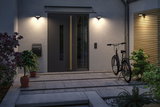 Trois appliques murales noires modernes avec lumière blanc chaud à l'entrée de la maison avec vélo et plantes.