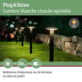 Lampes de jardin noires avec lumière blanche chaude sur pelouse près d’un mur en pierre pour ambiance extérieure