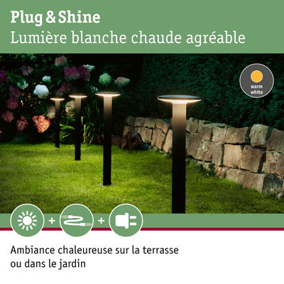 Lampes de jardin noires avec lumière blanche chaude sur pelouse près d’un mur en pierre pour ambiance extérieure