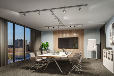 Modern conference room with grey chairs, large table, and adjustable silver ceiling spotlights.