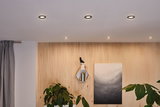 Six round recessed lights with warm white light in white ceiling above wooden panel wall with plants.