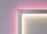 Hoekdetail van zilveren LED-wandlamp met warm wit licht en roze achtergrondverlichting