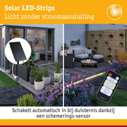 Zonne-LED-strips met zwart zonnepaneel en afstandsbediening in moderne tuin met zithoek