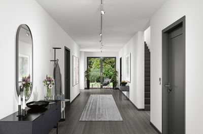 Moderner Flur mit grauem Boden, weißen Wänden, schwarzer Kommode und Paulmann LED-Deckenstrahlern.