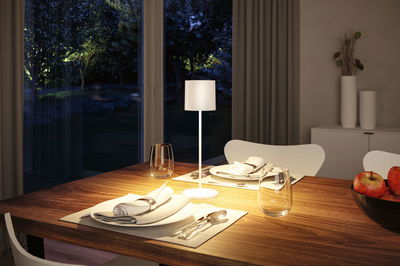 Modern white table lamp with fabric shade on wooden table, cozy dining room lighting
