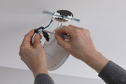 Installation d'un plafonnier LED blanc avec tournevis et câblage visible au plafond