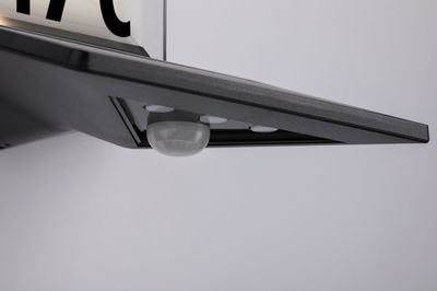 Black LED light panel with integrated motion sensor made of plastic for indoor use.