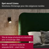 Spot mural noir Lirena avec tête pivotante sur mur en béton à côté d'un canapé vert en velours