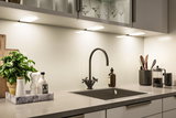 Modern kitchen countertop with black sink, matte black faucet and LED under-cabinet lighting