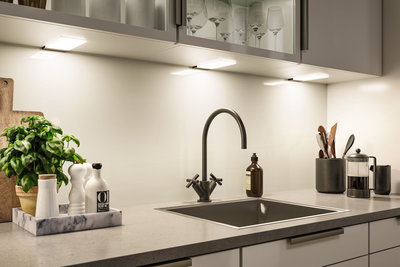 Modern kitchen countertop with black sink, matte black faucet and LED under-cabinet lighting