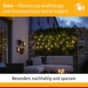 Gemütliche Terrasse mit Solar-Lichterkette an grüner Hecke und moderner Sitzgruppe bei Abendlicht
