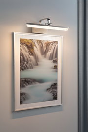 Applique LED moderne en acier inoxydable éclairant une photo de cascade sur mur gris pour intérieur