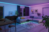 Modern living room with grey corner sofa and colorful LED strip lighting creating a cozy atmosphere