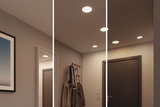 Three white LED ceiling lights in modern hallway with coat rack and dark door, warm white lighting
